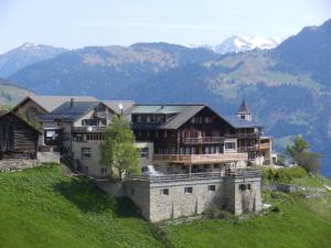 a large house on a hill with mountains in the background at Hotel Restaurant Capricorns in Wergenstein