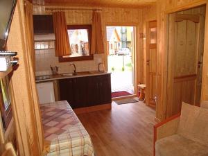 a small kitchen with a sink and a couch in a room at Domki Letniskowe Pikamar in Darlowko