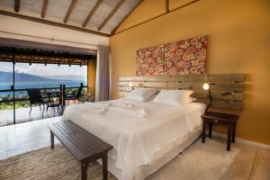 a bedroom with a large white bed and a balcony at Pousada Mariola in Ilhabela