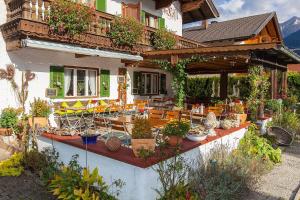 ein Gebäude mit einer Terrasse mit Stühlen und Topfpflanzen in der Unterkunft Frühstückspension Gästehaus Zum weissen Rössl in Wallgau
