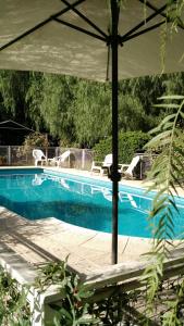 einen Pool mit Stühlen und einem Sonnenschirm daneben in der Unterkunft Residencial Castelar in Merlo