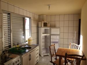 a kitchen with a table and a white refrigerator at Guarda Flats in Guarda do Embaú