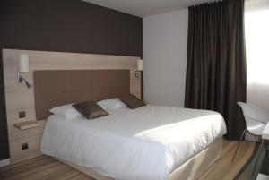 a bedroom with a large bed and a large window at Brit Hotel Vendée Mer in La Mothe-Achard