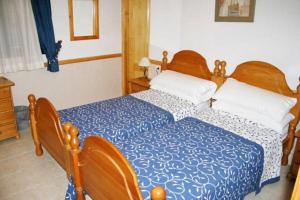 a bedroom with two beds with blue and white sheets at La Vista Pension in Guía de Isora