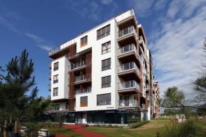 a tall white building with balconies and trees at Apartamenty Olimpic in Kołobrzeg