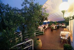 un patio con mesas y sillas y una tienda blanca en Hotel Claudio, en Bergeggi