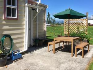 a picnic table with an umbrella next to a house at Shunters Cottage in Waihi