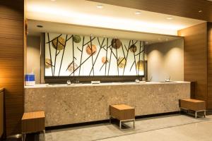 a bathroom with a mirror and a counter with benches at Dormy Inn Kumamoto Natural Hot Spring in Kumamoto