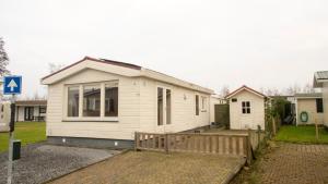 ein kleines weißes Haus mit einer Veranda im Hof in der Unterkunft Chaletparc Krabbenkreek in Sint-Annaland