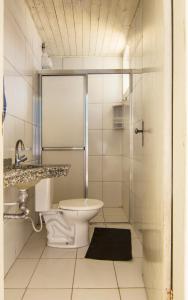 a white bathroom with a toilet and a shower at Hotel Marina Clube de Pesca in Cananéia