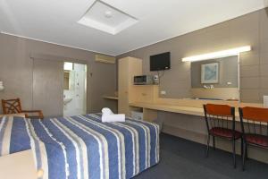 een hotelkamer met een bed en twee stoelen bij Tandara Hotel Motel in Sarina