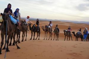 a group of people riding horses in the desert at Kasbah Tamariste in Merzouga
