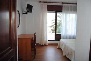 a bedroom with a bed and a desk and a window at Hostal Carabela in Areas