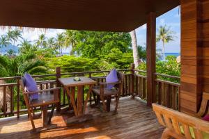 a porch with a table and chairs and the ocean at Palm Leaf Resort Koh Tao in Ko Tao