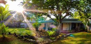 a house with the sun shining through the trees at Thambara Villa Unawatuna in Unawatuna