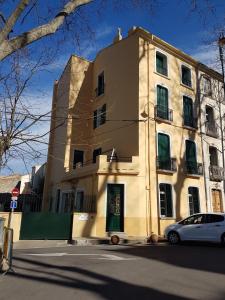 un bâtiment jaune avec une voiture garée devant lui dans l'établissement Maison Marijke, à Céret