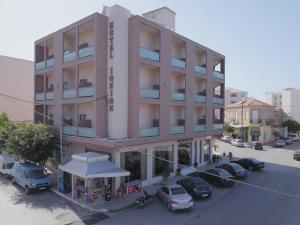 a tall building with cars parked in a parking lot at Ionion Hotel in Kyparissia