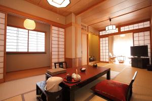 a living room with a table and a tv at Ryokan Yamanoyu in Minamioguni