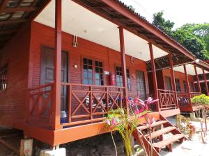 una pequeña casa roja con porche y algunas plantas en Senja Bay Resort en Perhentian Island