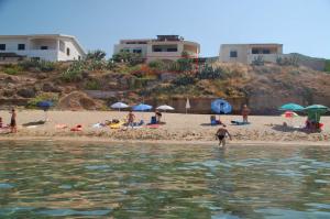 un grupo de personas en una playa con sombrillas en Villa Alabe - Waterfront Apartments in Bosa Porto Alabe, en Tresnuraghes