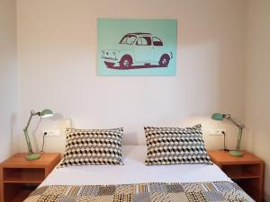 een slaapkamer met een bed met twee lampen en een foto van een busje bij Hôtel Des Bois in Seltz
