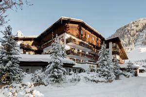 a large building with snow covered trees in front of it at Hotel La Perla: The Leading Hotels of the World in Corvara in Badia