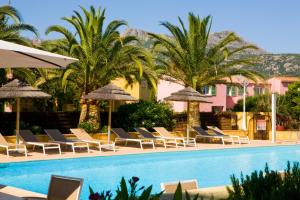 a pool with chairs and umbrellas and palm trees at Résidence Padro in Calvi