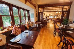 un restaurante con mesas y sillas de madera y ventanas en Chester Beatty Inn, en Ashford