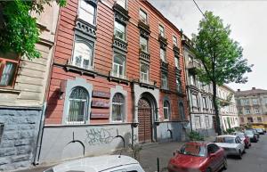 un edificio di mattoni rossi con macchine parcheggiate di fronte di Stylish Studio near Rynok square a Lviv