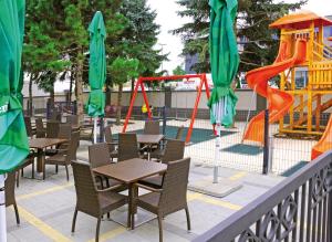 un ristorante con tavoli e sedie e un parco giochi di Hotel Calypso a Zagabria