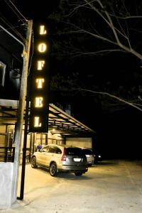 a hotel sign with a car parked in a parking lot at Loftel @ Nakhon in Nakhon Si Thammarat