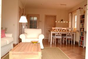 a living room with a table and a white chair at Ferienhaus Boddenkiek mit Wasserblick in Seedorf in Seedorf +37 photos