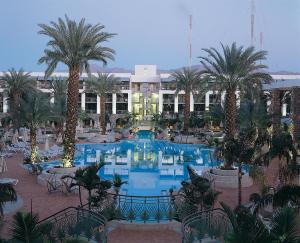 a large pool of water surrounded by palm trees at Agamim by Isrotel Collection in Eilat