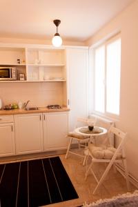 アルバ・ユリアにあるLa Garsonの白いキャビネット、テーブルと椅子付きのキッチンが備わります。