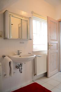 a white bathroom with a sink and a window at Ferienhaus Boddenkiek mit Wasserblick in Seedorf in Seedorf