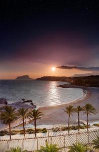 a beach with palm trees and the ocean at night at La Sort Boutique Hotel in Moraira