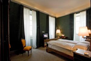 una camera con letto, sedia e finestre di Grand Hotel Della Posta a Sondrio