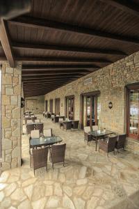 a patio with tables and chairs and a stone wall at Grand Meteora Hotel in Kalabaka