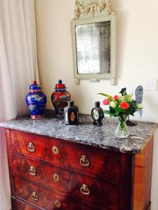 une commode avec des vases et des fleurs en haut dans l'établissement Chambres d'Hôtes et Gîtes du Château de Clauzuroux, à Champagne-et-Fontaine