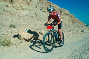 un hombre montando una bicicleta en un camino de tierra en Ramon Inn by Isrotel Collection, en Mitzpe Ramon