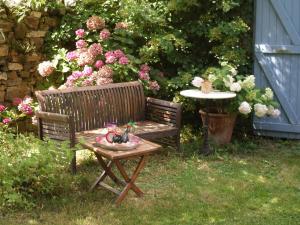 eine Holzbank mit einem Tisch im Garten in der Unterkunft La Belle Poule - SEBRIGHT in Villefranche-de-Rouergue
