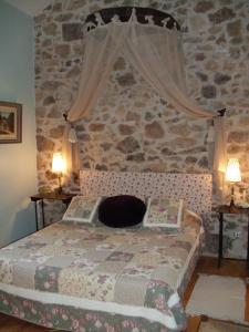 een slaapkamer met een bed met een stenen muur bij La Belle Poule - SEBRIGHT in Villefranche-de-Rouergue