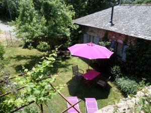 einen rosa Schirm und Stühle sowie einen Tisch im Hof in der Unterkunft La Belle Poule - SEBRIGHT in Villefranche-de-Rouergue