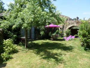 ヴィルフランシュ・ド・ルエルグにあるLa Belle Poule - SEBRIGHTのピンクの傘とテーブルと椅子が備わる庭
