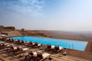 a pool with chairs on a deck with a view at Beresheet by Isrotel Exclusive in Mitzpe Ramon