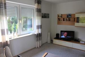 a living room with a tv and two windows at Ferienwohnungen Akzent in Papenburg