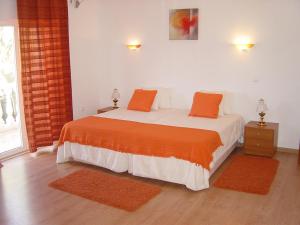 1 dormitorio con 1 cama con almohadas de color naranja en Casas da Vila, en Vimieiro