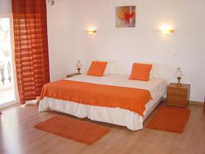 a bedroom with a bed with orange pillows on it at Casas da Vila in Vimieiro