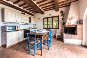 uma cozinha com uma mesa de madeira e cadeiras azuis em Agriturismo La Collina Dei Lecci em San Gimignano