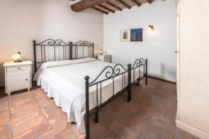 a bedroom with a bed with a white bedspread and a table at Agriturismo La Collina Dei Lecci in San Gimignano